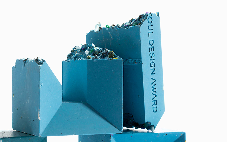 Campioni spezzati del trofeo Seoul Design Award sopra altre sculture blu, con frammenti colorati visibili all’interno